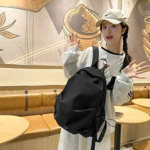 Detail view of large black nylon backpack featuring functional side drawstring adjustment
