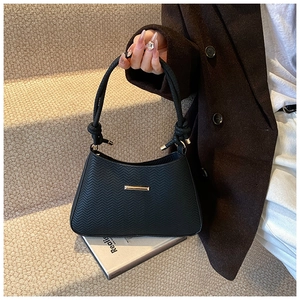 Detail of black chevron embossed shoulder bag with gold hardware and rope handle