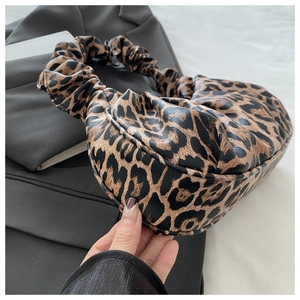 Detailed view of leopard print texture and pleated handle on the crescent hobo bag