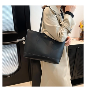 Close-up of minimalist black leather tote bag featuring sleek stitching and shoulder straps