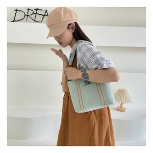 Detail of light green canvas tote bag with brown stripes and MIDU '2ND' branding