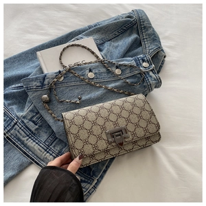 Detailed close-up of a vintage chain crossbody bag with clover print on denim fabric