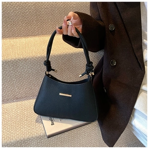 Detail of black leather handbag with V-shaped texture and golden metal hardware