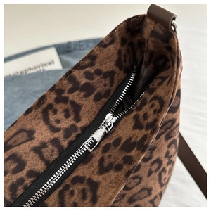 Detail view of leopard print faux fur bucket bag with silver zipper and brown strap