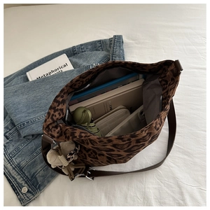 Macro shot of spacious leopard print bucket bag interior with books and cute bear charm