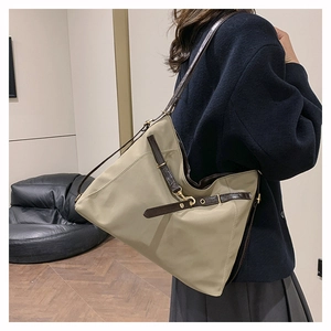 Detail of beige tote bag showing large capacity and brown leather shoulder strap texture