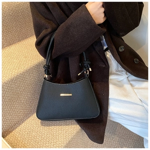 Close-up of black crossbody bag featuring chevron texture and knot strap detail