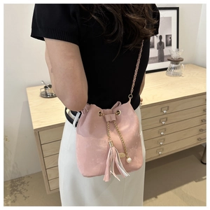 Detailed view of a pink drawstring bucket bag with tassel and pearl charms in a modern setting
