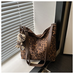Detail showing plush leopard print texture and brown adjustable leather strap of the bucket bag