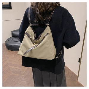 Close-up of khaki nylon backpack featuring premium dark brown leather straps and metal buckles
