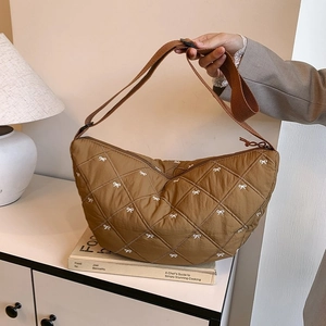 Detail einer braunen Hobo-Tasche mit Rautensteppung und bestickten weißen Schleifen