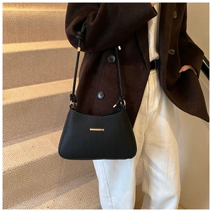 Detail of black chevron quilted shoulder bag with gold logo and knotted strap detail