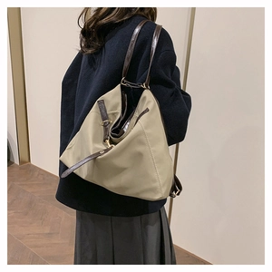 Detail view of the khaki tote bag with dark brown leather straps and metal buckle accents