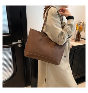 Detail of a large brown leather tote bag with fine texture and stylish metal label