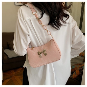 Detailed close-up of pink patent leather shoulder bag with silver bow buckle and resin chain