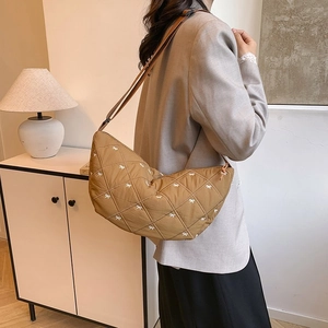 Detailansicht der braunen gesteppten Mondtasche mit weißer Schleifenstickerei auf Textil