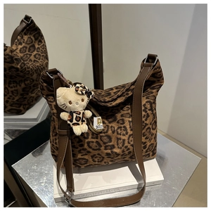 Detail view of leopard print hobo bag with brown leather strap and plush cat charm