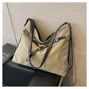 Detail of khaki nylon tote bag with brown faux leather trim and gold hardware accents