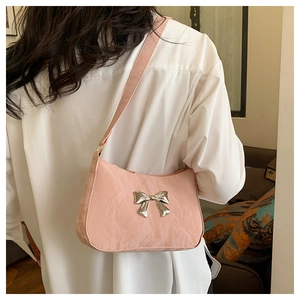 Pink hobo bag with pleated texture and silver bow detail worn over the shoulder