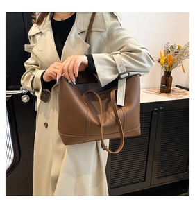Close-up of brown leather tote bag with gold stamped text and dual carrying straps