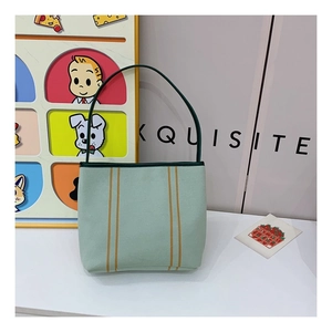 Detailed view of canvas tote bag with orange stripes and dark green leather handles