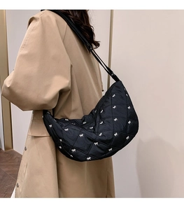 Detail einer schwarzen gesteppten Halbmond-Tasche mit weißen Schleifen-Stickereien