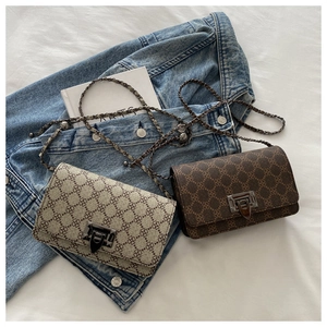 Close-up of vintage leopard print crossbody bags with chain straps on denim and white fabric