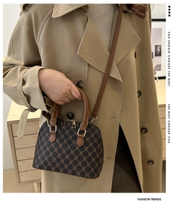 Brown shell bag with classic monogram print and gold double zipper detail on a trench coat