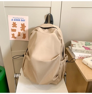 Detail of warm khaki nylon backpack side pocket with black adjustable drawstring