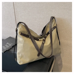 Detail of army green tote bag with deep brown leather straps and gold metal hardware