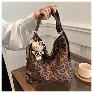 Detailed shot of large leopard print hobo bag with wide brown strap and plush charm