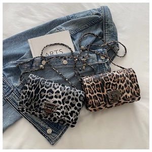 Close-up of leopard print crossbody bags with bronze rotary locks and chain straps