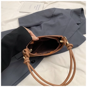 Detail view of brown shoulder bag interior featuring a zip pocket and knotted strap design