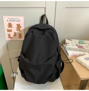 Detail of minimalist black nylon backpack with side drawstring pocket and durable fabric texture