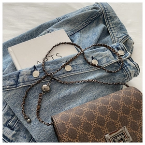 Close-up of vintage brown patterned crossbody bag with metal chain and turn-lock
