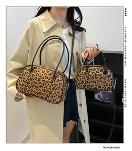 Detailed view of two leopard print handbags in different sizes held by a model