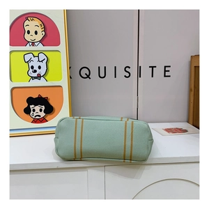 Detail view of woven green canvas tote bag featuring yellow vertical stripes and texture
