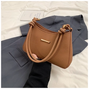 Close-up of caramel brown shoulder bag with wave texture and gold metal accents