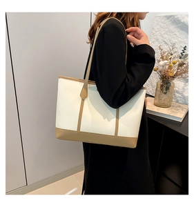 Detail view of large minimalist tote bag with beige leather and camel shoulder straps