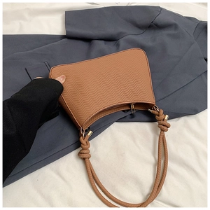 Detailed view of caramel shoulder bag featuring wavy texture and knotted handle design