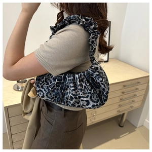 Close-up of leopard print crescent bag with ruffled shoulder strap and pleated velvet details