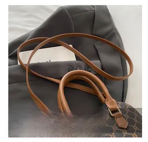 Close-up of brown monogram shell bag showing leather handle and gold-tone zipper hardware