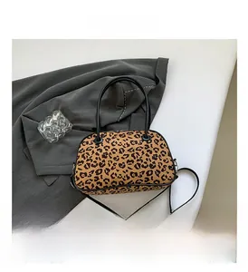 Top view of leopard print handbag with dual handles on a grey suit and white surface