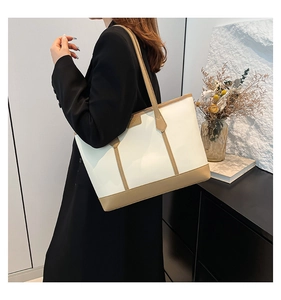 Detailed side view of a large tote bag with contrast khaki trim worn by a model