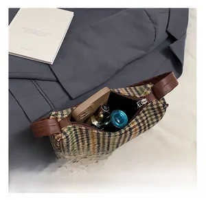 Detail showing the internal storage capacity of the plaid underarm bag with daily items