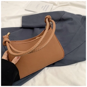 Detail of caramel brown embossed shoulder bag with unique knotted handle and gold metal links