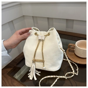 Detail of cream bucket bag with golden chain, fringe tassel and pearl pendant