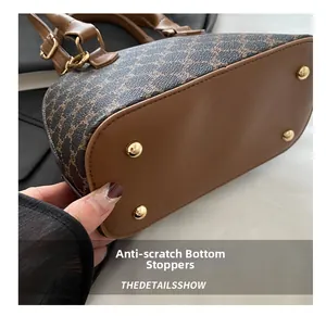 Detail view of the shell bag bottom showing golden protective metal studs and leather