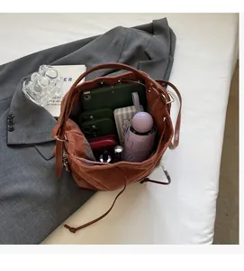 Top view of spacious brown suede bucket bag interior holding an iPad and accessories