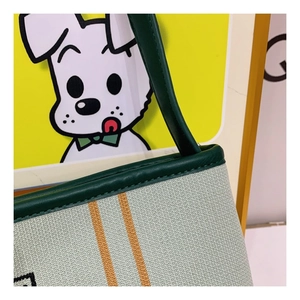 Detail of light green knit tote bag with orange stripes and green leather handle stitching